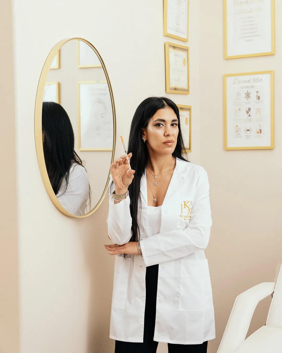Koral beside the round gold mirror in the KM RX Aesthetics studio, Bellaire