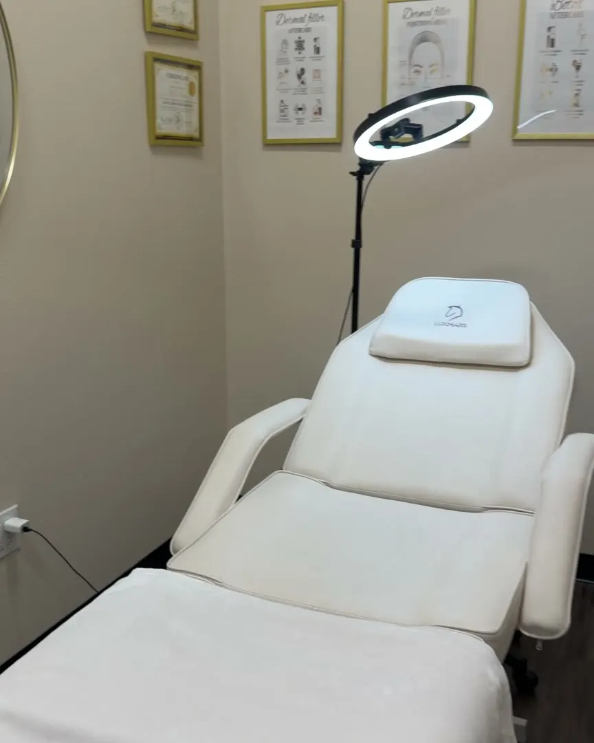 The KM RX treatment room: white bed, ring light and framed facial anatomy sketches